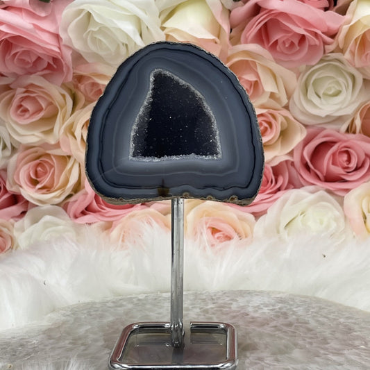 Natural agate geode on stand showing banded chalcedony and crystal-lined interior