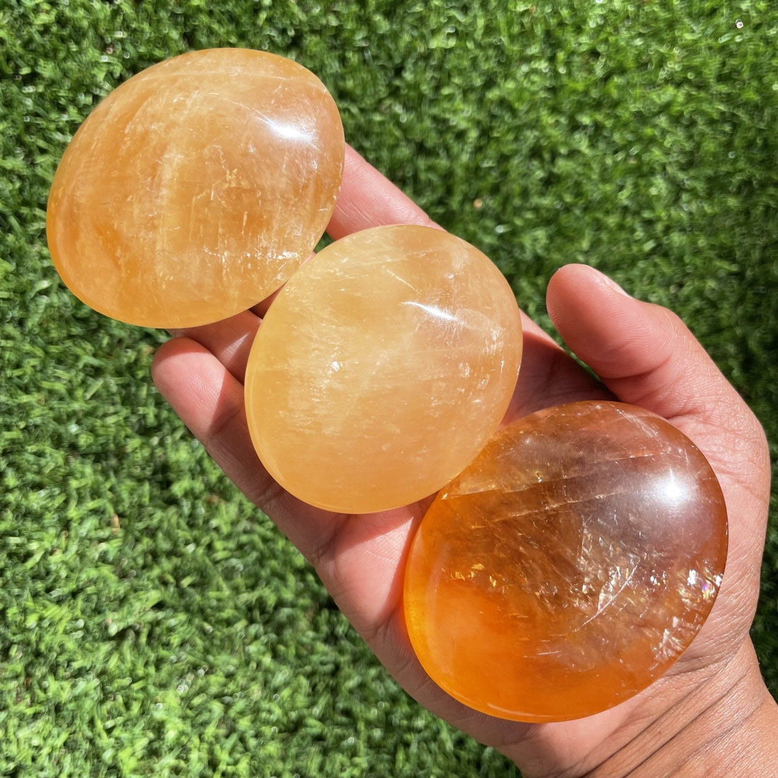 Large banded orange calcite palm stone showing waves of deep and pale orange