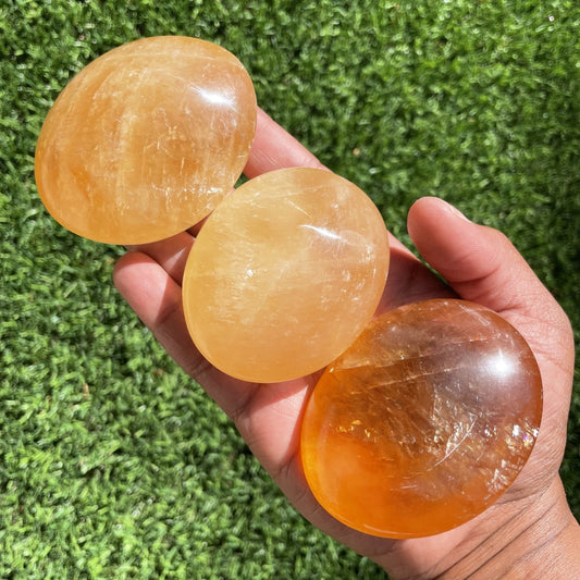 Large banded orange calcite palm stone showing waves of deep and pale orange